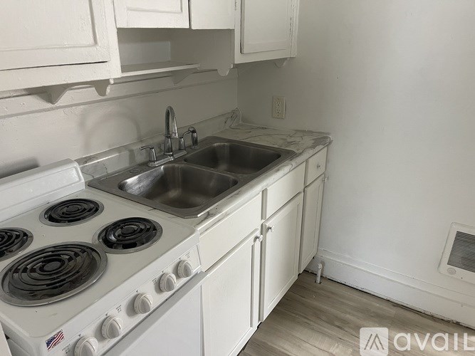 A white kitchen with a stove top oven and a sink.