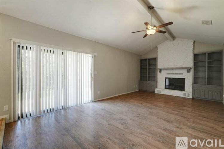 A spacious living room with a fireplace and a ceiling fan.