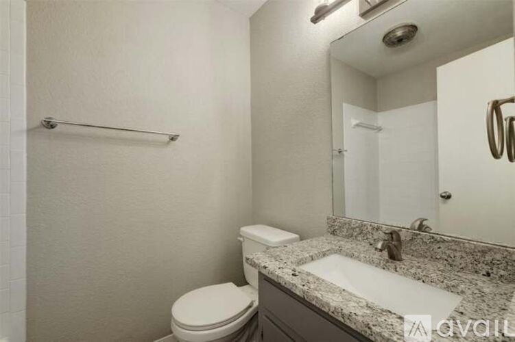 A bathroom with a toilet, sink, and mirror.