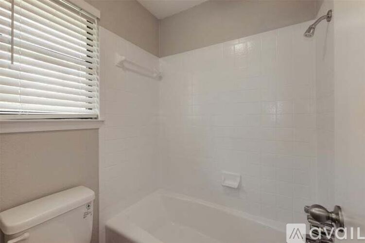 A white bathroom with a toilet, tub, and shower.
