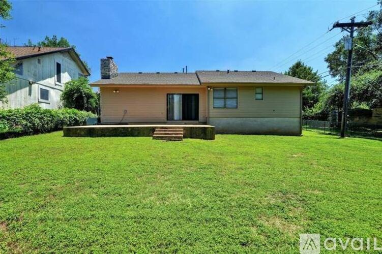 A house with a brown roof and a brown door is surrounded by a green lawn.