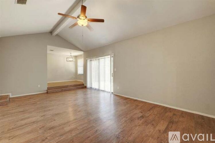 A spacious room with wooden flooring and a ceiling fan.