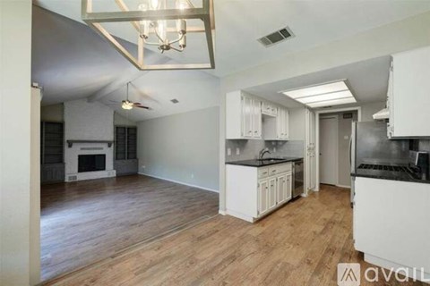 A kitchen with white cabinets and a wooden floor.