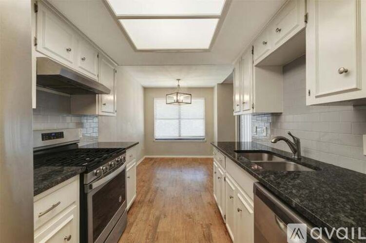 A kitchen with white cabinets and black countertops.
