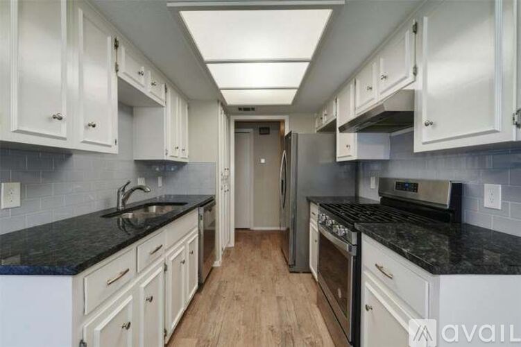 A kitchen with white cabinets and black countertops.