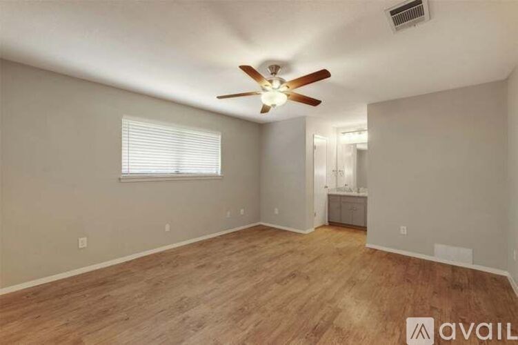 A room with a ceiling fan and wooden flooring.