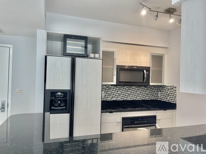 A modern kitchen with a black countertop and a microwave above it.