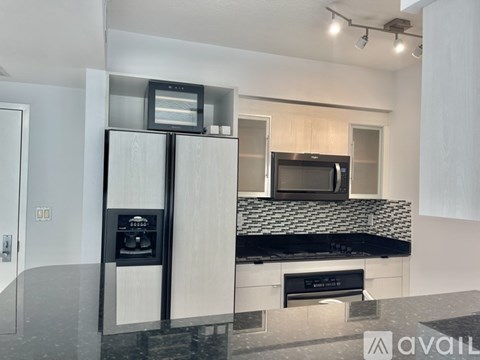 A modern kitchen with a black countertop and a microwave above it.