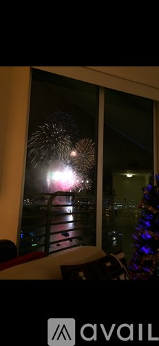A window with a view of fireworks in the night sky.