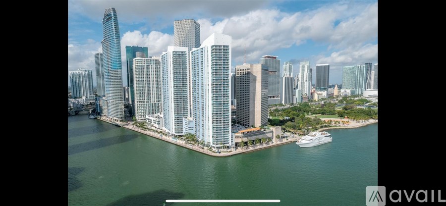 A cityscape with tall buildings and a body of water in the foreground.