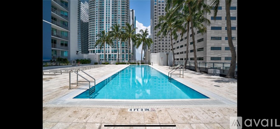 A pool surrounded by buildings and palm trees.