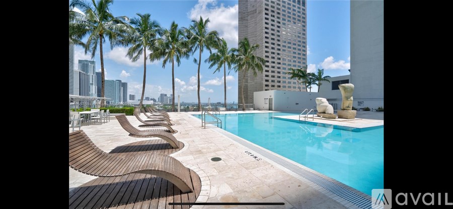 A pool surrounded by palm trees and lounge chairs.