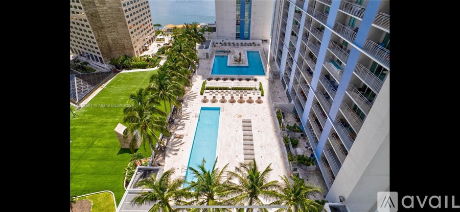 A pool surrounded by palm trees and a white building.
