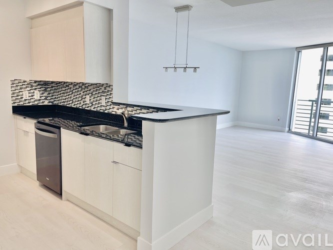 A kitchen with a black and white tiled backsplash and white cabinets.