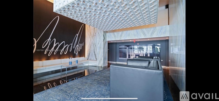 A room with a blue carpet and a wall with a large signature on it.