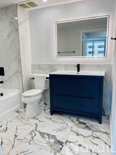 A white toilet sits next to a white bathtub in a bathroom with a marble floor.