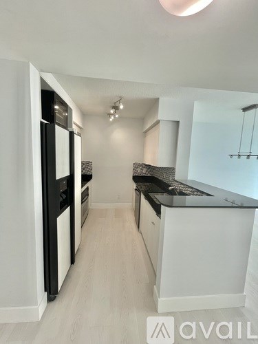 A modern kitchen with white cabinets and a black countertop.