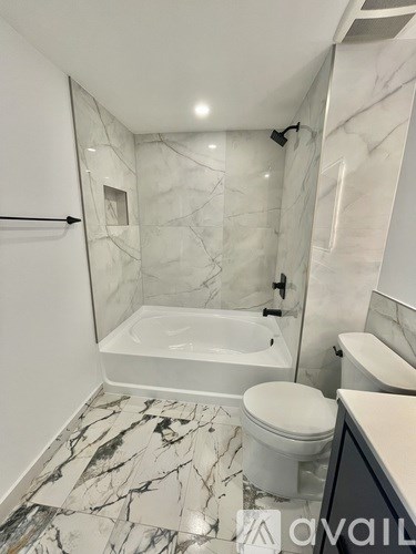 A bathroom with a marble floor and white fixtures.