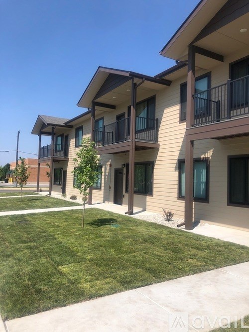 A row of modern townhouses with balconies and green lawns.