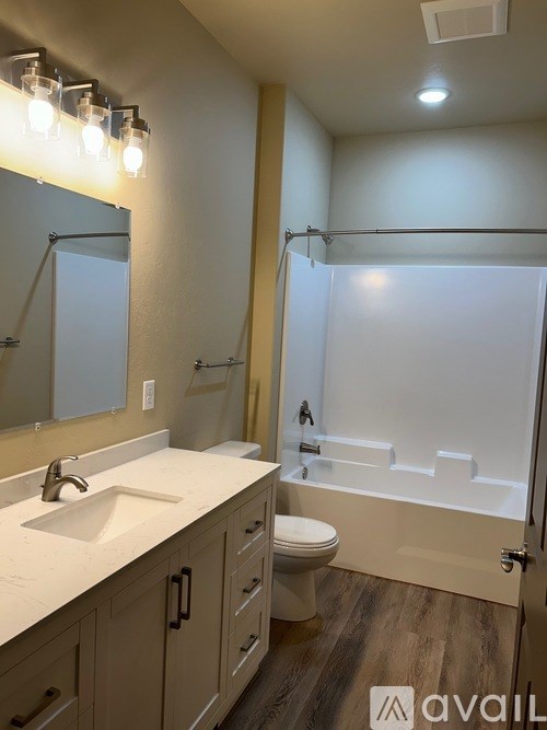 A bathroom with a sink, mirror, toilet, and bathtub.