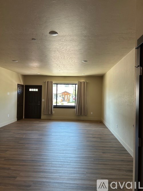 A room with wooden flooring and a window with curtains.