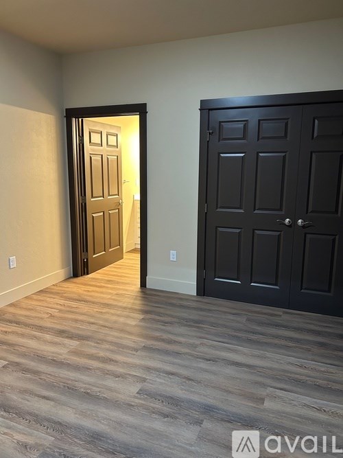 A room with a black door and a wooden floor.