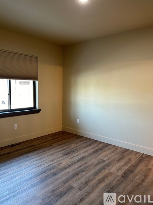 A room with wooden flooring and a window with blinds.