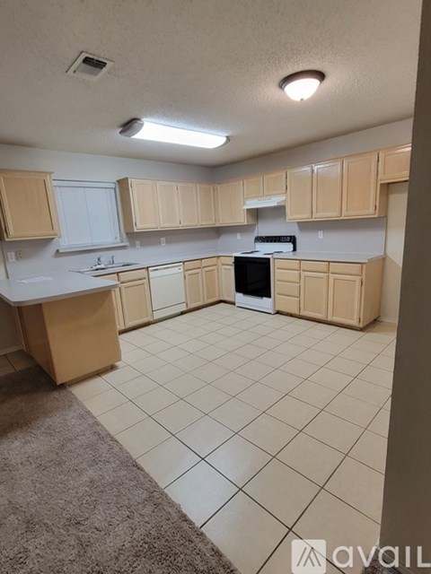 A kitchen with white appliances and beige cabinets.