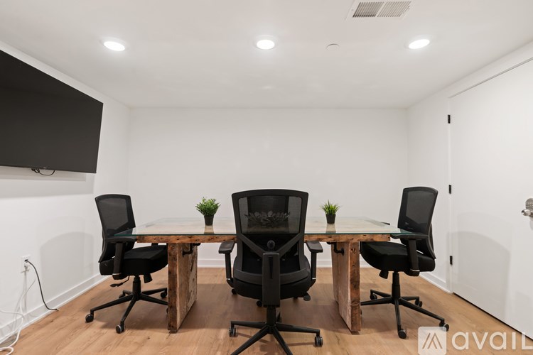 A conference room with a white table and four black chairs.
