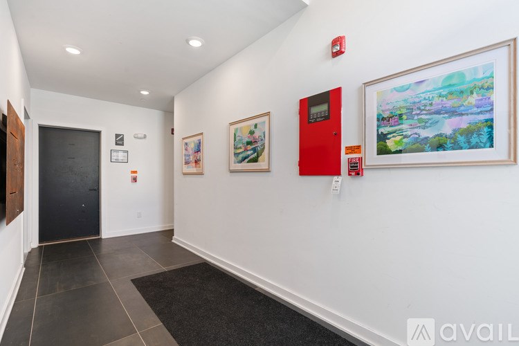 A hallway with a red door and two paintings on the wall.