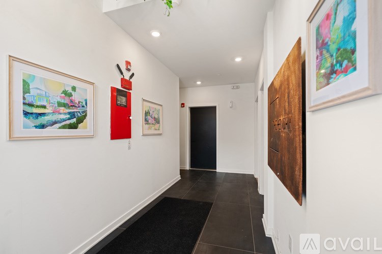 A hallway with a red object on the wall and a painting on the wall.