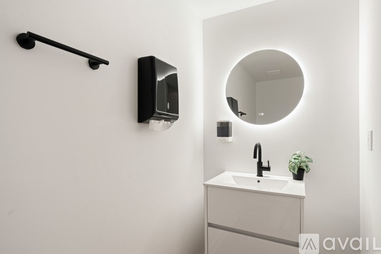 A bathroom with a sink, mirror, and a black towel rack.