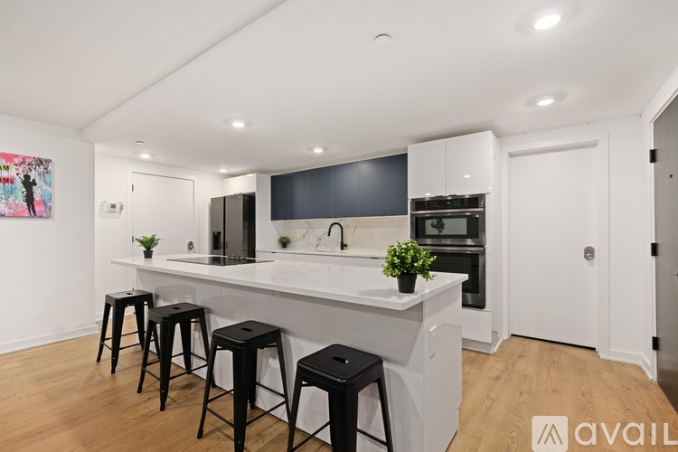 A kitchen with white cabinets and black stools.
