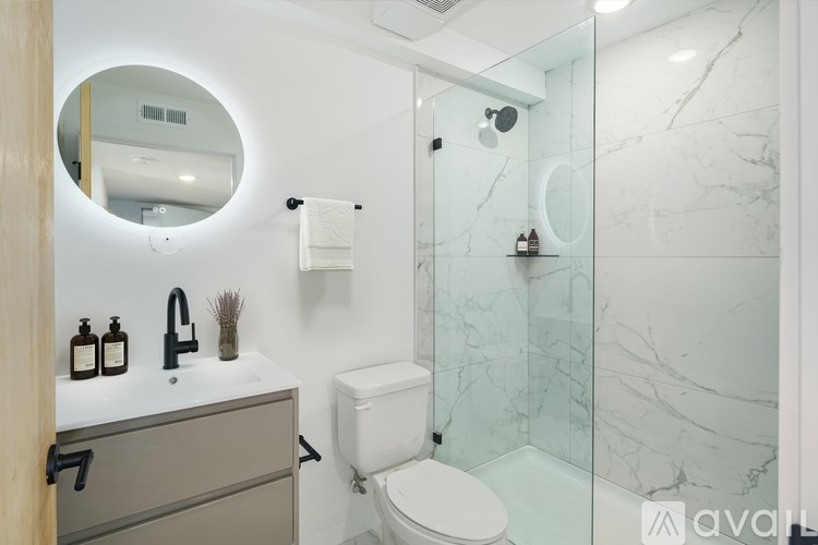 A bathroom with a marble wall and a round mirror.