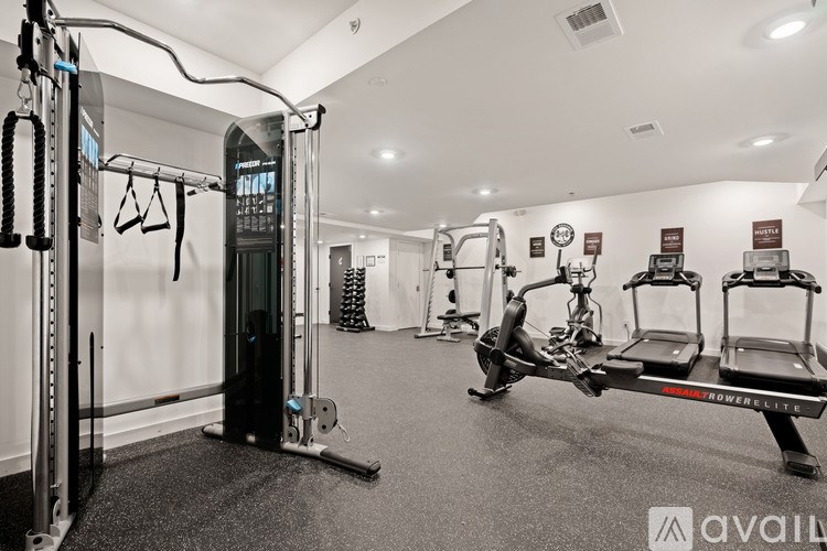 A gym with a variety of equipment including a squat rack, a leg press machine, and a rowing machine.