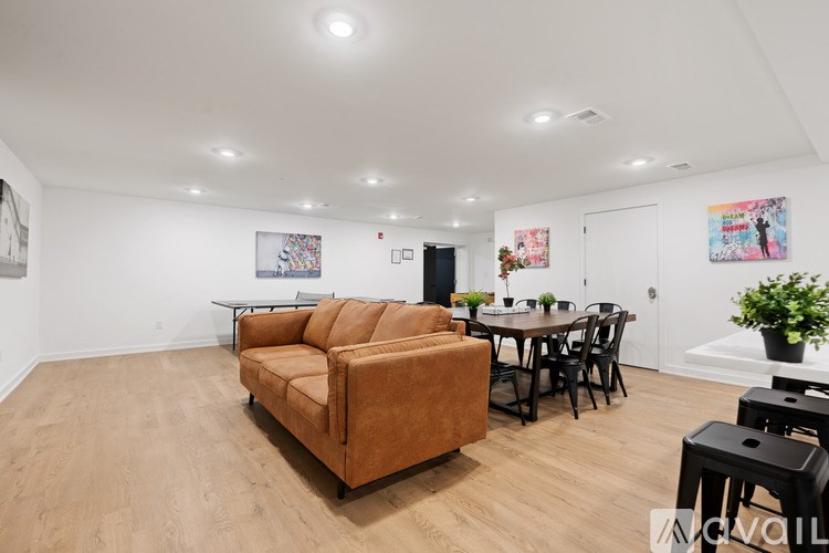 A living room with a brown couch, a dining table with chairs, and a potted plant.