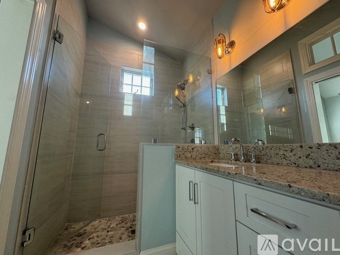 A bathroom with a walk-in shower and a vanity with a granite countertop.