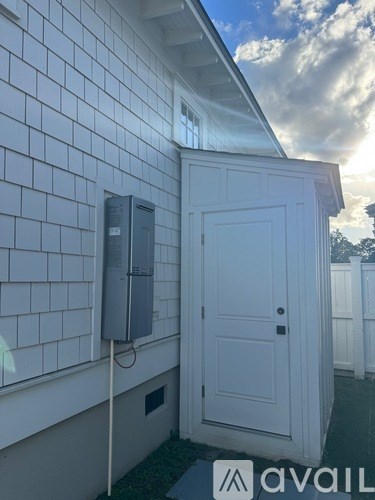 A white door is on the side of a house with a grey electrical box on the wall.