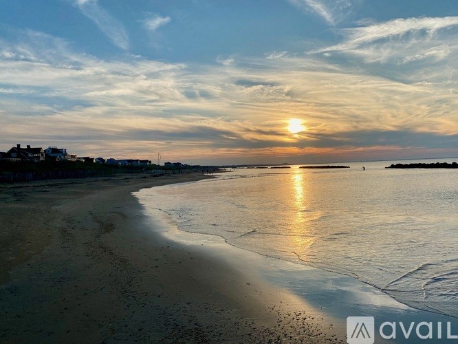 A beach at sunset with the sun reflecting on the water.