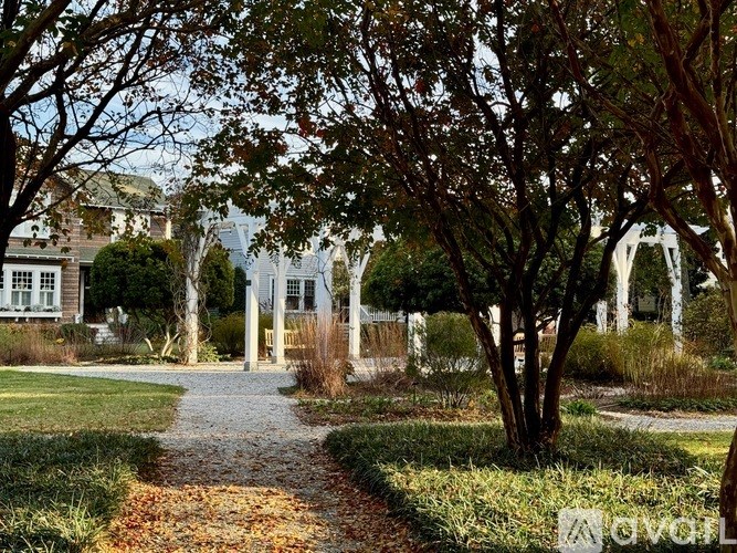 A pathway leads through a garden to a white arched structure.