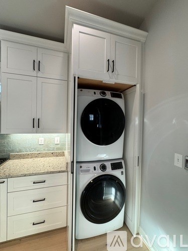 A white washing machine is in a cabinet in a laundry room.