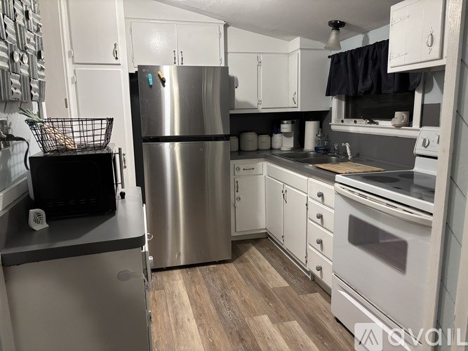 A kitchen with a stainless steel refrigerator and white cabinets.
