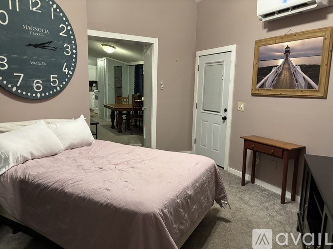 A bedroom with a bed, a table, and a clock on the wall.