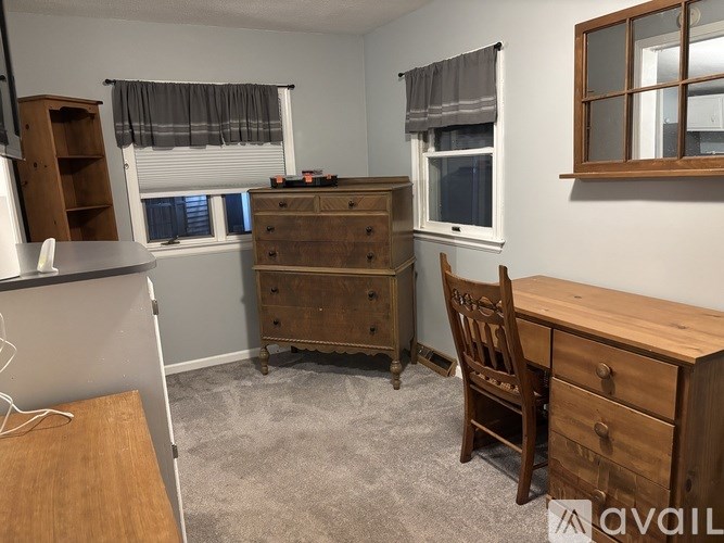 A room with a desk, chair, and two windows.