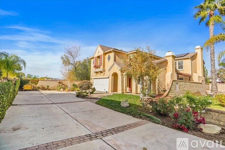 A house with a driveway and a palm tree in front.