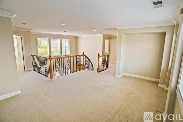 A spacious living room with a staircase and a window.