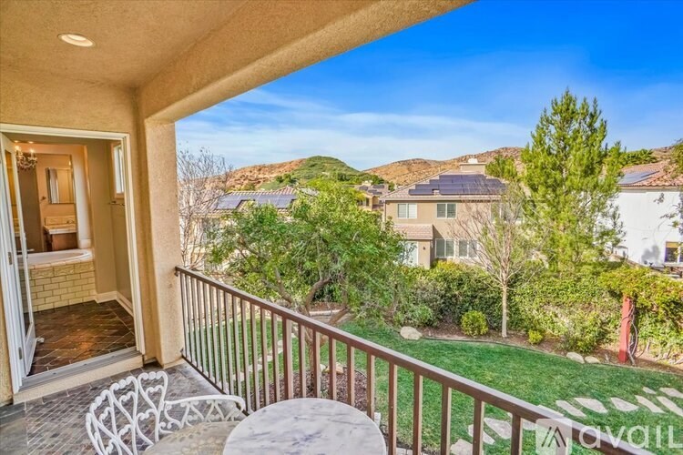 A balcony with a table and chairs overlooks a residential area.