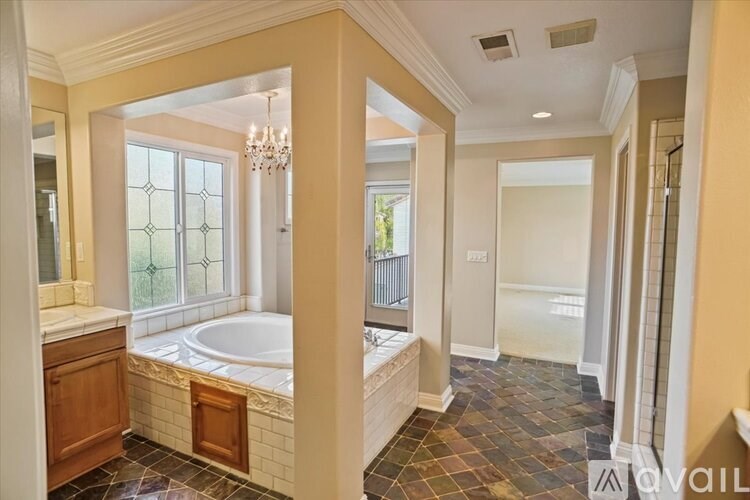 A bathroom with a tub, sink, and a chandelier.