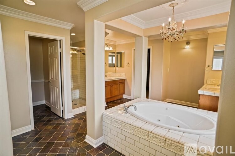 A bathroom with a large tub and a chandelier.