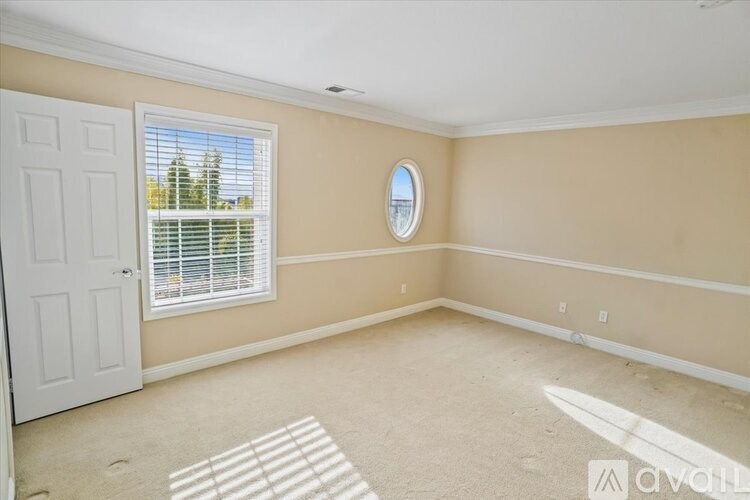 A room with a round mirror on the wall and a door on the left.